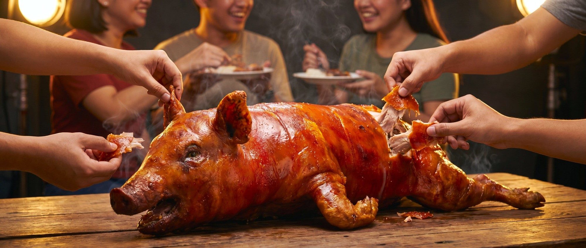 Friends reaching in together to share pieces of a whole Cebu lechon at a party table